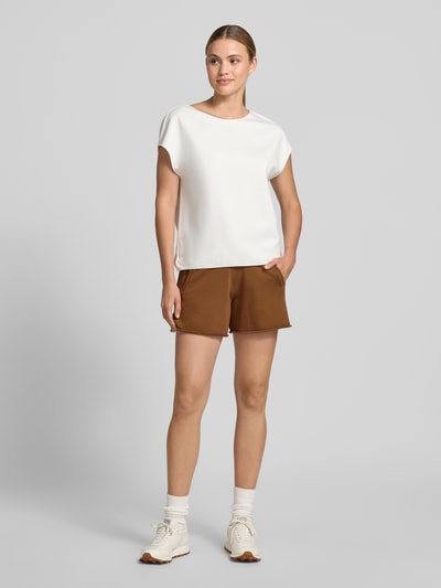 Frauenmodel trägt Sweatshorts mit Eingrifftaschen von Rich & Royal aus Baumwoll-Mix mit Stretch-Anteil, Relaxed-Fit, elastischer Bund und Tunnelzug, Farbe Braun, glatte Textur, kombiniert mit weißem Damen T-Shirt, Innenbeinlänge bei Größe S: 14 cm, Ganzkörperansicht von vorne.