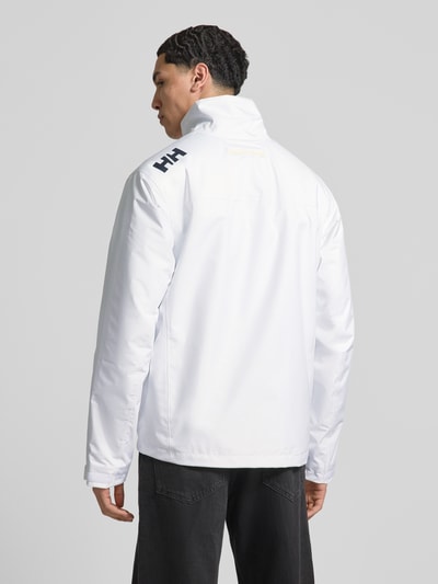 Männermodel trägt weiße Midlayer Jacke mit Stehkragen Modell 'CREW' von Helly Hansen, Gerader-Schnitt, Rückenansicht, glatte Textur.