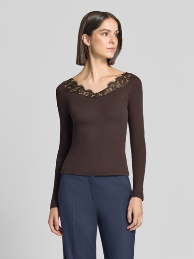 Frauenmodel trägt Slim Fit Longsleeve aus reiner Baumwolle von Rich & Royal, braun mit Spitzenbesatz, V-Ausschnitt, Ganzkörperansicht von vorne.
