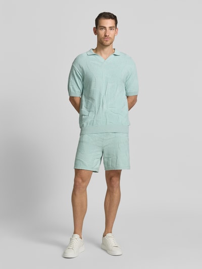 Männermodel trägt Regular Fit Sweatshorts aus Baumwoll-Mix Modell 'ASURFER' von BOSS Orange, Optik: Unifarben, Struktur, Label-Patch, Bundabschluss elastisch mit Tunnelzug, Eingrifftaschen, Materialverarbeitung: Frottee, Farbe Hellgrün, Ganzkörperansicht von vorne.