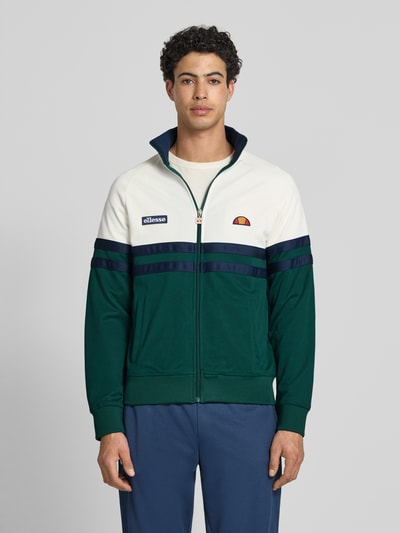 Männermodel trägt Sweatjacke aus Baumwoll-Mix Modell 'RIMINI' von Ellesse in Grün, Weiß und Dunkelblau, Gerade Passform, Stehkragen, durchgehender Reißverschluss, Label-Details, elastische Abschlüsse, Ganzkörperansicht von vorne.