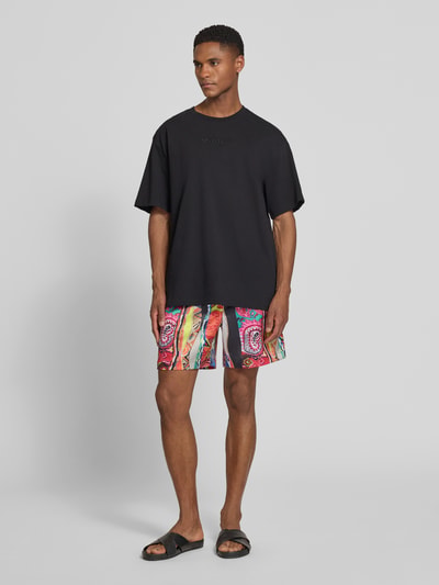 Männermodel trägt Straight Fit Shorts mit elastischem Bund Modell 'Resort' von COLUCCI, bunte Farben, elastischer Material-Mix, Ganzkörperansicht von vorne.