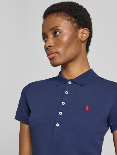 Frauenmodel trägt Slim Fit Poloshirt aus Baumwoll-Mix von Polo Ralph Lauren in Dunkelblau, rotes Logo, glatte Textur, Nahaufnahme Oberkörper. Damen Poloshirt von Polo Ralph Lauren.