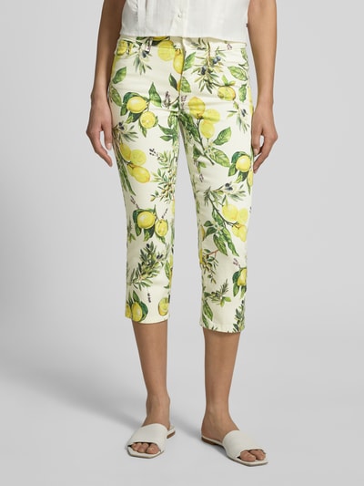 Kobieta nosi Slim Fit Jeans mit floralem Allover-Print von Marc Cain, mieszanka bawełny, krój slim fit, 5 kieszeni, zapięcie na guzik i zamek błyskawiczny, szerokość w rozmiarze 36: 38 cm, długość wewnętrzna nogawki w rozmiarze 36: 53 cm, kolor ecru z kwiatowym nadrukiem na całej powierzchni, widok całej sylwetki z przodu.