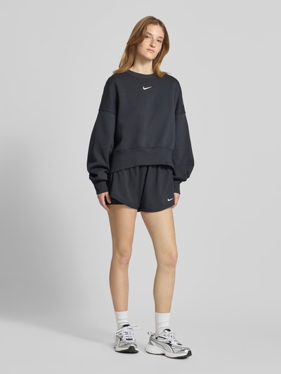 Frauenmodel trägt schwarze Damen Shorts im 2-in-1-Look mit Logo Modell 'One' von NIKE TRAINING, Regular-Fit, elastischer Bund, Ganzkörperansicht von vorne.