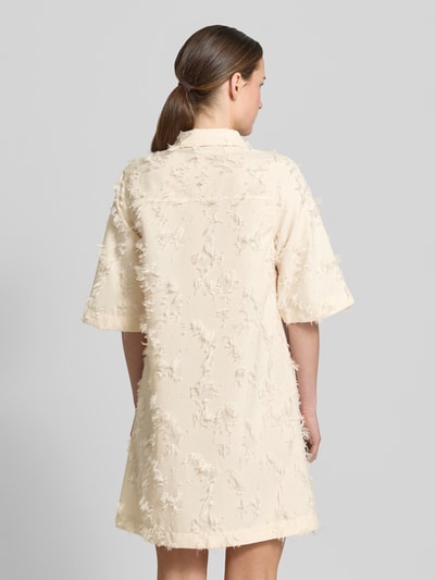 Frauenmodel trägt Minikleid mit kurzer Knopfleiste Modell 'Mialle' von mbyM in Creme mit Strukturmuster, gerader Schnitt, Ganzkörperansicht Rückansicht.