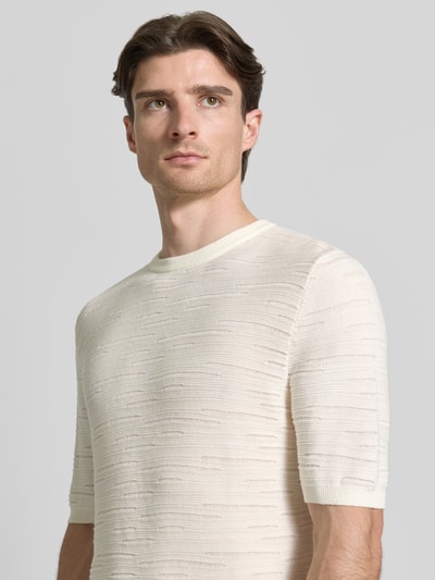 Männermodel trägt Strickshirt aus Baumwolle von Antony Morato, cremefarben, runder Ausschnitt, Halbarm, Nahaufnahme Oberkörper.