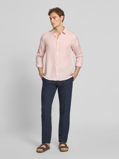 Męski model nosi Regular Fit Freizeithemd aus reinem Leinen od s.Oliver RED LABEL, jasnoróżowy, gładki len, koszulowy kołnierzyk, długi rękaw, widoczne zapięcie na guziki, logo-patch, całkowita sylwetka z przodu.