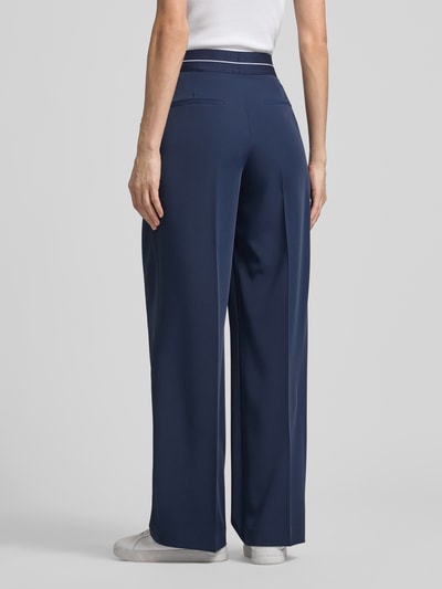 Modelka nosi Hose mit elastischem Bund und Label-Detail von JOOP!, mieszanka materiałów z dodatkiem streczu, krój regular fit, elastyczny pas, detal z logo, szerokość w rozmiarze 36: 38 cm, długość wewnętrzna nogawki w rozmiarze 36: 81 cm, granatowy kolor, proste nogawki, gładka tekstura, całkowity widok z tyłu.