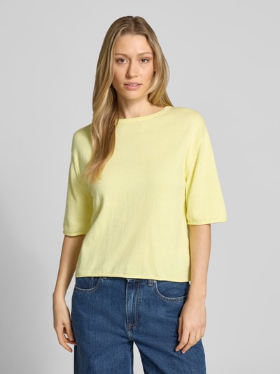Modelka nosi Oversized Pullover aus Baumwoll-Kaschmir-Mix von Tom Tailor, efekt: jednolity kolor, krój oversized, okrągły dekolt, krótki rękaw, zrolowany brzeg, dzianina, mieszanka bawełny i kaszmiru, jasny żółty kolor, tekstura miękka, jednokolorowy, widok całej sylwetki z przodu