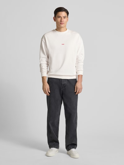 Männermodel trägt Regular Fit Sweatshirt aus reiner Baumwolle Modell 'DUBRAXO' von HUGO, Optik: Unifarben, Motiv-Print, Ganzkörperansicht von vorne.