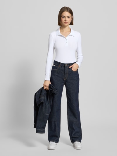 Vrouwenmodel draagt Slim Fit Langarmshirt aus Baumwoll-Mix Modell 'KITTE' van Pieces in effen wit met polokraag en ribbelstructuur, Ganzkörperansicht von vorne.
