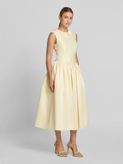 Frauenmodel trägt Midikleid mit Umlegekragen von Self-Portrait, Taillierte Passform, Zierschleife, Ärmelloses Design, ausgestellte Passform, cremefarbener Stoff, glatte Textur, Ganzkörperansicht von vorne.