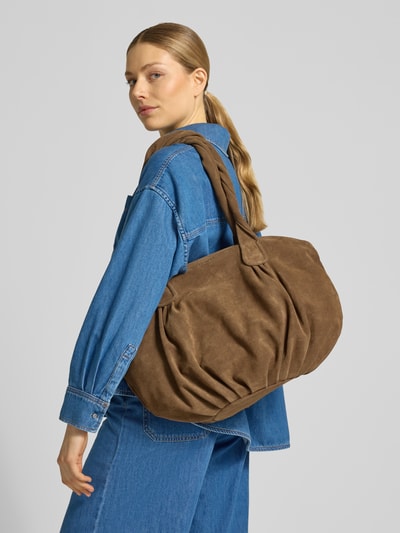 Kobiece modelka nosi torbę shopper z wytłoczonym logo w imitacji skóry welurowej, model 'Lucy' od LIEBESKIND BERLIN, szerokość w rozmiarze 1: 50 cm, długość w rozmiarze 1: 33 cm, głębokość w rozmiarze 1: 22 cm, długość paska na ramię: 72 cm, główna przegroda zapinana na zamek błyskawiczny, kolor brązowy, miękka tekstura, widok od tyłu w pełnej sylwetce.