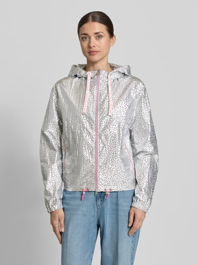 Frauenmodel trägt Jacke mit Kapuze Modell 'MAY' von Frieda & Freddies in silber mit Kordelzug, Zweiwege-Reißverschluss, Seitliche Reißverschlusstaschen, elastische Ärmelabschlüsse, Gerader-Schnitt, Glanzoptik, Ganzkörperansicht von vorne. Rückenlänge bei Größe 36: 58 cm, Schulterbreite: 50 cm, Brustweite: 56 cm, Ärmellänge: 63 cm.