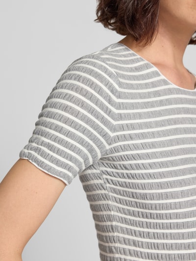 Frauenmodel trägt T-Shirt aus Viskose-Mix mit Rundhalsausschnitt von Emporio Armani, grau-weiß gestreift, Strukturmuster, Nahaufnahme Oberkörper.