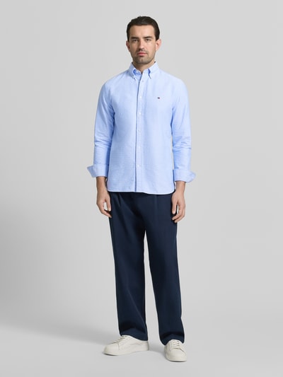 Männermodel trägt Regular Fit Freizeithemd aus reiner Baumwolle von Tommy Hilfiger in Hellblau mit Button-Down-Kragen, Ganzkörperansicht von vorne.