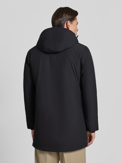 Męski model ma na sobie Regular Fit Parka mit Logo-Print von Lindbergh, czarny kolor, elastyczna mieszanka materiałów, gładka tekstura, kaptur z tunel, zamek błyskawiczny, Długość tyłu w rozmiarze M: 90 cm, szerokość ramion w rozmiarze M: 50 cm, szerokość klatki piersiowej w rozmiarze M: 58 cm, długość rękawów w rozmiarze M: 65 cm, widok całej sylwetki z tyłu.