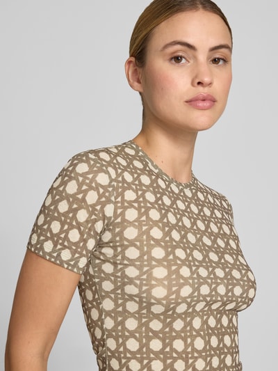 Frauenmodel trägt Slim Fit T-Shirt mit Rundhalsausschnitt von Nanushka, geometrischer Allover-Print, semitransparent, kurzärmelig, Nahaufnahme Oberkörper.