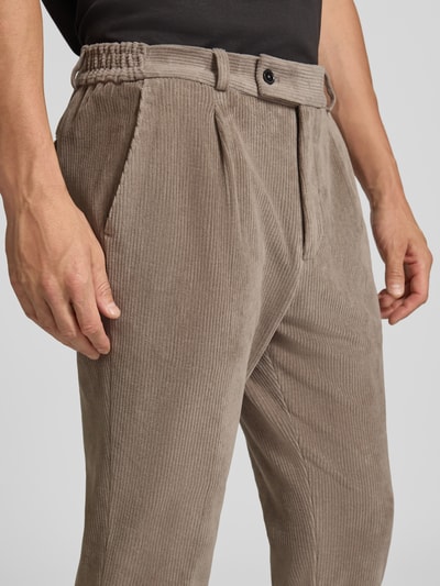Männermodel trägt Slim Fit Hose aus Baumwoll-Mix in Cord-Optik Modell 'Cliffer' von Zuitable, Nahaufnahme Oberkörper, elastischer Bund, sichtbare Taschen, strukturierte Oberfläche, dezenter Braunton, Herrenhose, Kontext: elastischer Baumwoll-Mix, Slim Fit, Cord-Optik, Eingriff- und Gesäßtaschen, Knopf- und Reißverschluss, Bundweite 37 cm, Innenbeinlänge 76 cm.