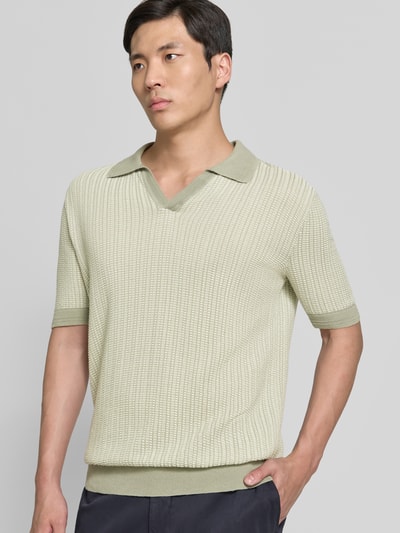 Männermodel trägt Regular Fit Poloshirt aus Baumwoll-Leinen-Mix Modell 'SEEROY' von HUGO in hellgrün mit Allover-Strukturmuster, Nahaufnahme Oberkörper.