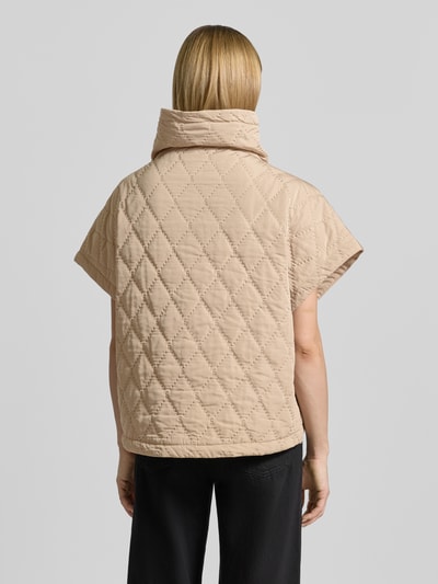 Frauenmodel trägt Cape mit Steppnähten und Eingrifftaschen von Copenhagen Muse in Beige, Relaxed-Fit, Rückansicht, Ganzkörperansicht. Rückenlänge 66 cm, Schulterbreite 42 cm, Brustweite 25 cm bei Größe S/M.