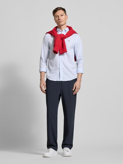 Mannelijk model draagt Regular Fit Vrijetijdsoverhemd uit katoenpopeline van Tommy Hilfiger met streepmotief, all-over look, button-downkraag, doorlopende knoopsluiting, gestikt logo, achterpas met stolpplooi, lange mouw, manchet met één knoop, afgeronde rompzoom, puur katoen, lichte kleuren en gladde textuur. Ganzkörperansicht van voren.