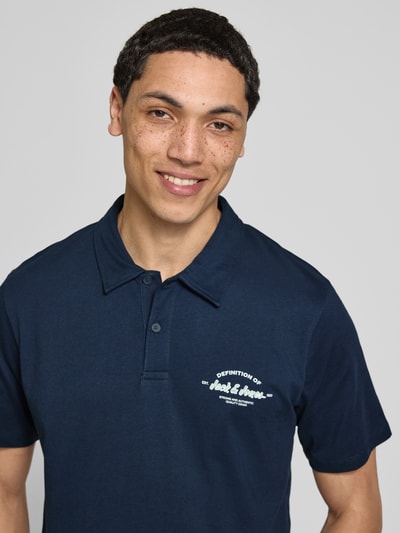 Männermodel trägt poloshirt van puur katoen regular fit model 'BRANDON' van Jack & Jones met polokraag, korte knoopsluiting en labelprint, ruglengte bij maat M 71 cm, nahaufnahme bovenlichaam.