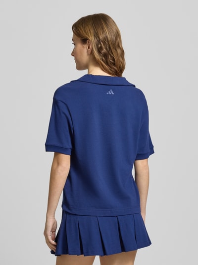 Frauenmodel trägt Poloshirt mit Label-Stitching von adidas Sportswear in Dunkelblau aus reiner Baumwolle, lockerer Schnitt, Ganzkörperansicht Rückansicht.