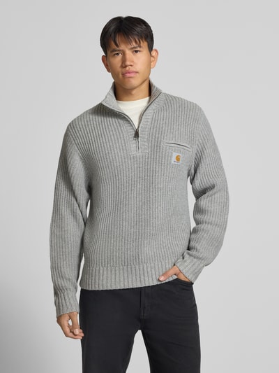 Männermodel trägt grauen Troyer mit Brustleistentasche Modell 'DETROIT' von Carhartt Work In Progress, grobe Strickstruktur, Ganzkörperansicht von vorne.