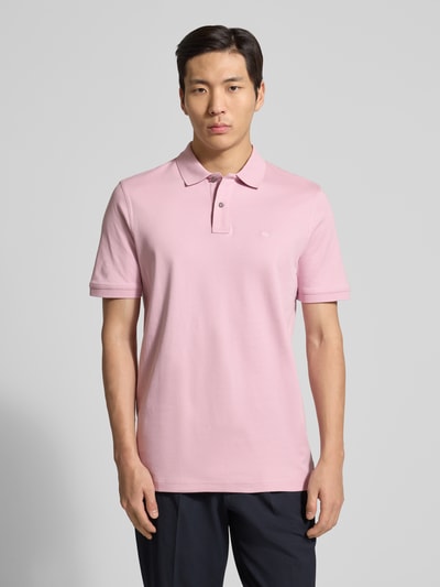 Männermodel trägt Regular Fit Poloshirt mit Logo-Stitching von Fynch-Hatton in Rosa, reine Baumwolle, kurze Knopfleiste, Ganzkörperansicht von vorne.