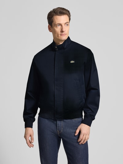 Männermodel trägt Regular Fit Bomberjacke mit Baumwoll-Anteil Modell 'HARRINGTON' von Lacoste, Optik: Unifarben, Ganzkörperansicht von vorne.