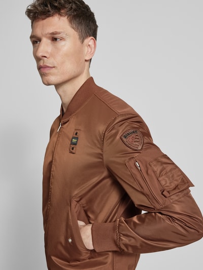 Männermodel trägt Jacke mit Zweiwege-Reißverschluss Modell 'Rocky' von Blauer Usa in Braun, Regular-Fit, Stehkragen, Pattentaschen, Nahaufnahme Oberkörper. Rückenlänge 65 cm, Schulterbreite 46 cm, Brustweite 58 cm, Ärmellänge 65 cm.
