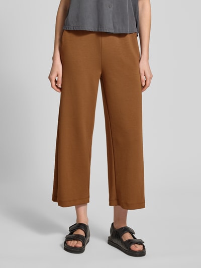 Kobiece modelka nosi spodnie dresowe Wide Fit Sweatpants in verkürzter Passform Modell 'Banu' od Soyaconcept, elastyczna mieszanka materiałów z domieszką modalu, krój wide fit, skrócony, pas z tunelem, brązowy kolor, gładka tekstura, pełen widok z przodu.