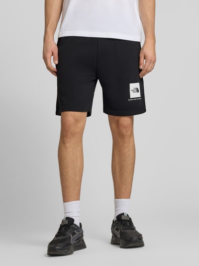 Männermodel trägt Regular Fit Shorts mit Eingrifftaschen von The North Face, Schwarz, Baumwoll-Mix, Bundweite 40 cm, Innenbeinlänge 18 cm, Ganzkörperansicht von vorne.
