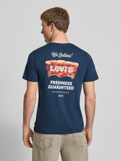 Männermodel trägt T-Shirt mit Label-Detail und Logo-Print von Levi's®, reine Baumwolle, körpernaher Schnitt, Ganzkörperansicht Rückansicht.
