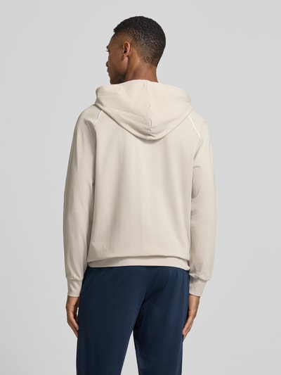 Männermodel trägt unifarbene Regular Fit Sweatjacke aus Baumwoll-Mix von BOSS mit Kapuze und Kontraststreifen, Ganzkörperansicht Rückansicht.