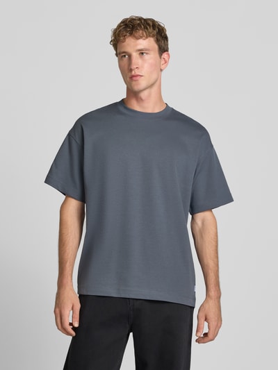 Männermodel trägt T-Shirt mit Rundhalsausschnitt Modell 'BARRON' von Jack & Jones in Dunkelgrau, Baumwoll-Mix, Relaxed Fit, Ganzkörperansicht von vorne