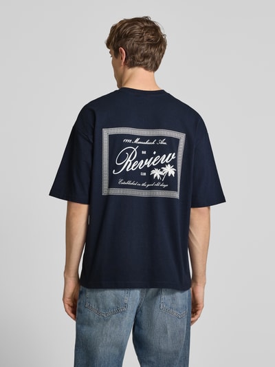 Männermodel trägt T-Shirt mit Rundhalsausschnitt und Label-Print von REVIEW in Dunkelblau aus Reine Baumwolle, Relaxed-Fit, Ganzkörperansicht Rückansicht. Rückenlänge bei Größe M: 71 cm.