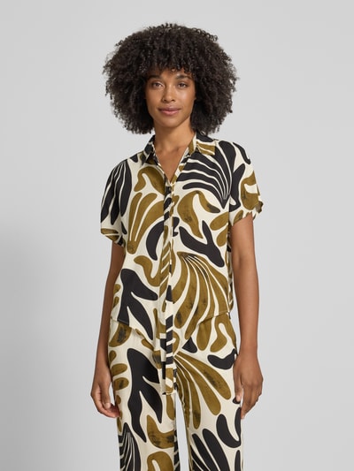 Frauenmodel trägt Regular Fit Bluse aus Viskose mit Knotendetail Modell 'FELDI' von Soyaconcept im Allover-Look mit Hemdblusenkragen, verdeckter Knopfleiste, kurzen Ärmeln, abstraktem Muster in Schwarz, Weiß und Braun, fließende Textur, Ganzkörperansicht von vorne. Rückenlänge bei Größe S: 54 cm, Ärmellänge bei Größe S: 10 cm.