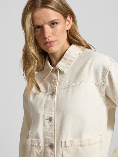Frauenmodel trägt Jeansjacke mit Eingrifftaschen Modell 'RACHEL' von JJXX aus reiner Baumwolle in Beige, Nahaufnahme Oberkörper.