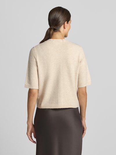 Frauenmodel trägt Regular Fit Cardigan in Strick-Optik Modell 'Iga' von VILA, beige Töne, glatte Textur, 1/2-Arm, Ganzkörperansicht Rückansicht.