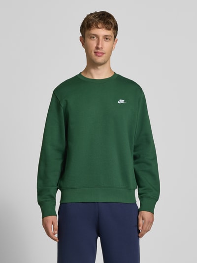 Männermodel trägt dunkelgrünes Relaxed Fit Sweatshirt aus Baumwoll-Mix von Nike mit feiner Struktur, Ganzkörperansicht von vorne, Herren Sweatshirt von Nike.