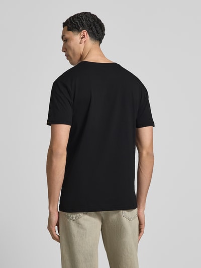 Männermodel trägt Herren T-Shirt mit Label-Detail Modell 'Basic' von Alpha Industries in Schwarz, Reine Baumwolle, Gerader-Schnitt, Rückenlänge 67 cm bei Größe M, Ganzkörperansicht Rückansicht.
