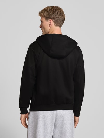 Männermodel trägt Sweatjacke mit Reißverschluss Modell 'COFUSION' von JACK & JONES in Schwarz, lockere Passform, Rückansicht, KI-modifiziertes Bild. Material-Mix mit Baumwoll-Anteil, Kapuze mit Stehkragen, elastische Abschlüsse.