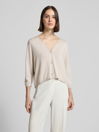 Frauenmodel trägt Schimmernde Strickjacke mit 3/4-Arm von Comma, Relaxed-Fit, V-Ausschnitt, Knopfleiste, cremefarben, Ganzkörperansicht von vorne.
