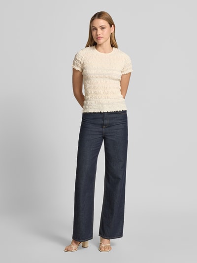 Frauenmodel trägt T-Shirt mit Smok-Details und Muschelsaum von Jake*s Casual, Baumwoll-Mix mit Stretch-Anteil, körpernaher Schnitt, Rundhalsausschnitt, Rückenlänge 52 cm bei Größe S, sanfte Beige-Töne, feine Struktur, ganzkörperansicht von vorne.