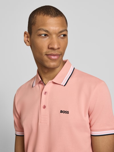 Männermodel trägt Regular Fit Poloshirt aus reiner Baumwolle Modell 'PADDY' von BOSS Green in Rosa, Piqué-Struktur, Nahaufnahme Oberkörper.