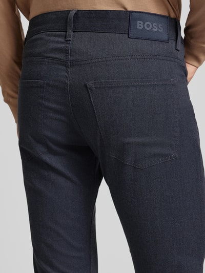 Männermodel trägt Slim Fit Stoffhose mit Baumwoll-Anteil Modell 'DELAWARE5' von BOSS, Optik: Allover-Muster, Label-Patch, Detailaufnahme Rückansicht.
