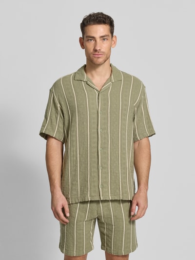 Männermodel trägt Regular Fit Freizeithemd mit Streifenmuster von MCNEAL aus reiner Bio-Baumwolle, grün-beige, Reverskragen, Knopfleiste, Ganzkörperansicht von vorne.